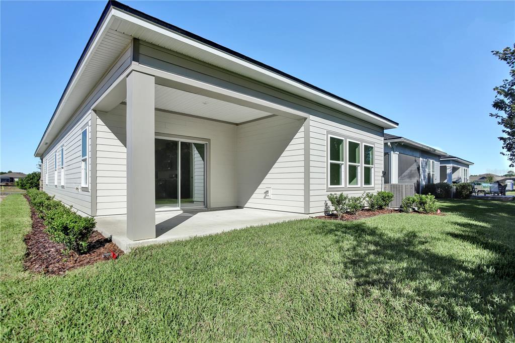 A light-colored house exterior features a covered concrete patio, sliding glass doors, and horizontal siding — 121 BEES KNEES WAY, ST AUGUSTINE, FL