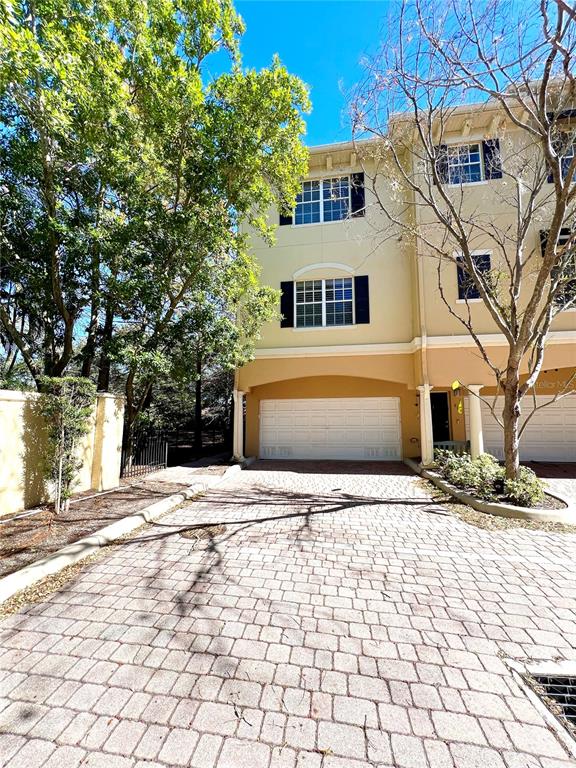 A three-story townhouse with a paved driveway and a two-car garage — 809 HARBOR OAK LANE, CLEARWATER, FL