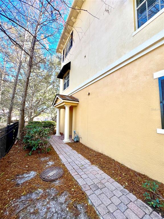 A paved walkway leads to a covered entryway on the side of a tan building — 809 HARBOR OAK LANE, CLEARWATER, FL