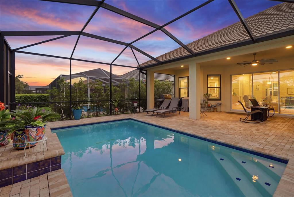 A screened-in patio features a swimming pool, lounge chairs, and a paved deck at sunset — 1800 N ROSE HUE PATH, HERNANDO, FL