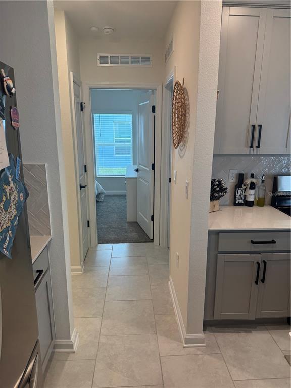 A tiled hallway leads to a bedroom, flanked by kitchen cabinetry with light gray finishes — 2127 GREEN VALLEY STREET, DAYTONA BEACH, FL