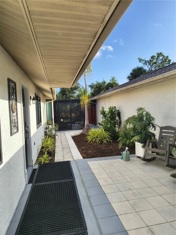 A paved patio area sits between two exterior walls of a house with a garden — 255 BOUNDARY BOULEVARD UNIT 104, ROTONDA WEST, FL