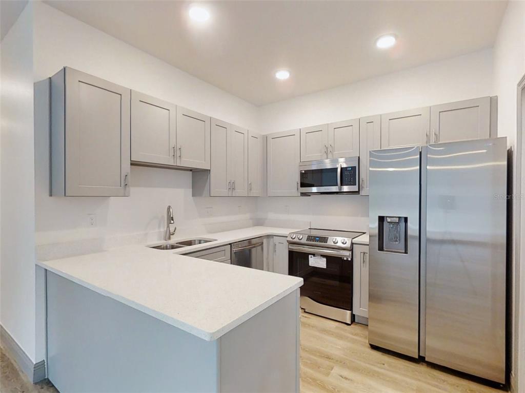 A kitchen features light gray cabinets, stainless steel appliances, and white countertops — 2 GUAVA LANE, OCKLAWAHA, FL