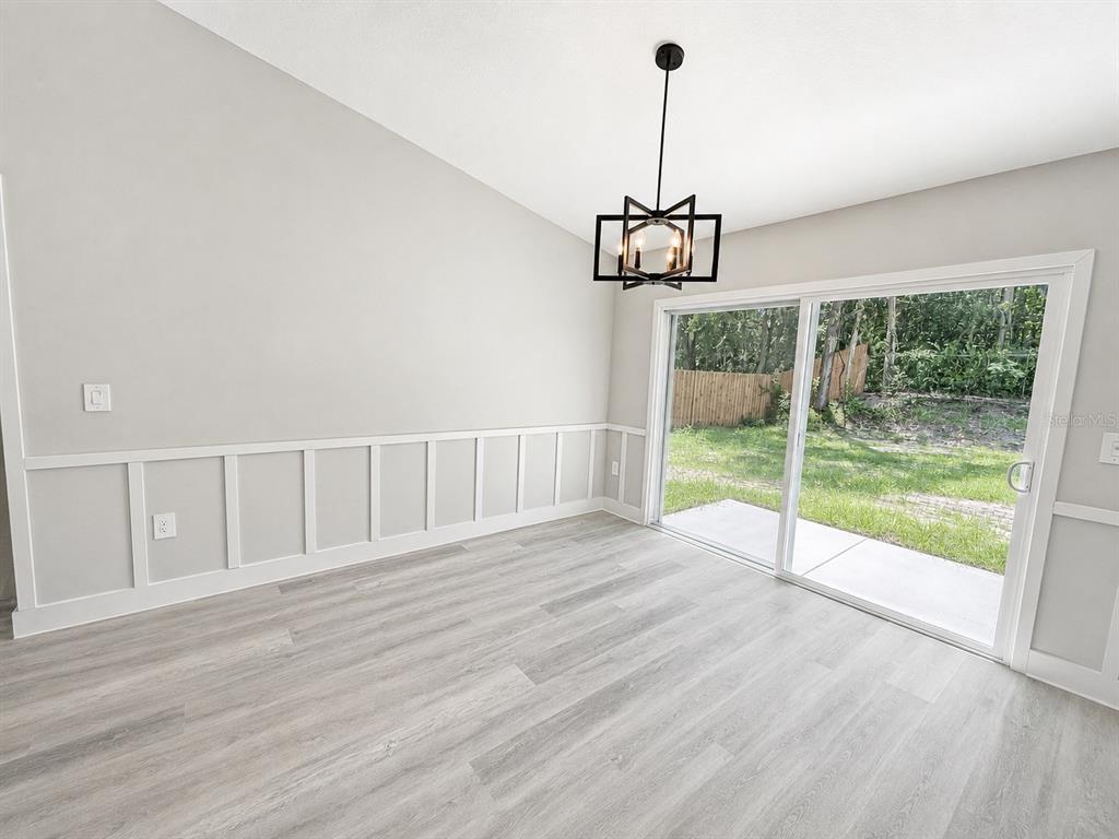 An empty bedroom features light gray walls, wood-look flooring, a tray ceiling, and a ceiling fan — 12744 SE 102ND TERRACE, BELLEVIEW, FL