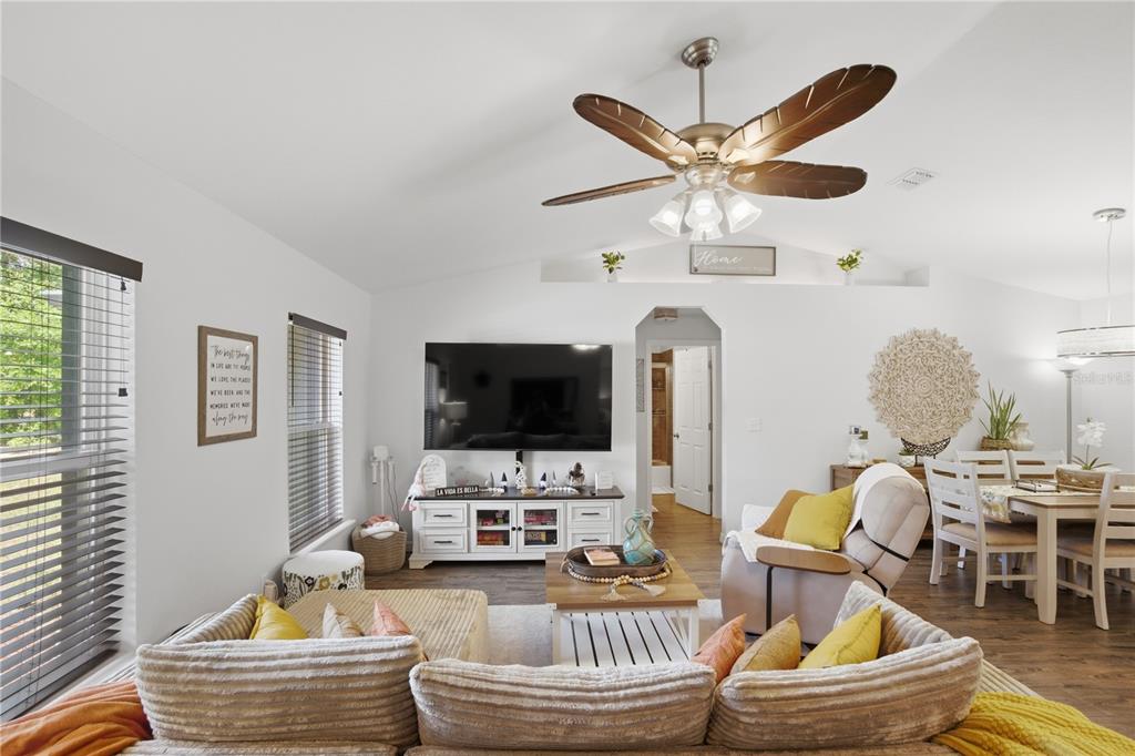 A living room features a vaulted ceiling, a ceiling fan, a television, and a dining area — 21635 SW 82ND LOOP, DUNNELLON, FL
