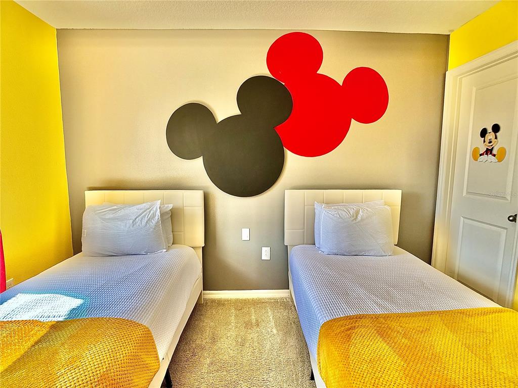A bedroom features two twin beds, yellow accent walls, and Mickey Mouse wall art — 5117 KILLARNEY WAY, KISSIMMEE, FL