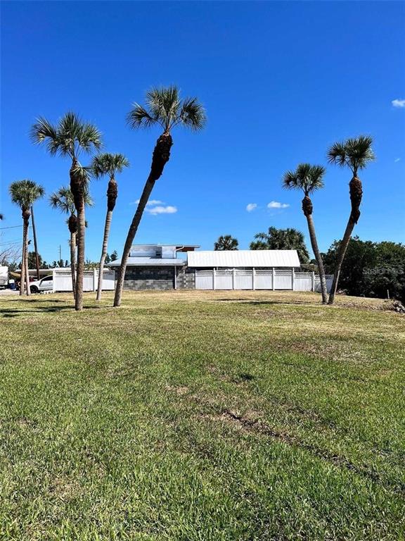 A grassy lot features several tall palm trees in front of a white-fenced house — ROSE STREET, VENICE, FL