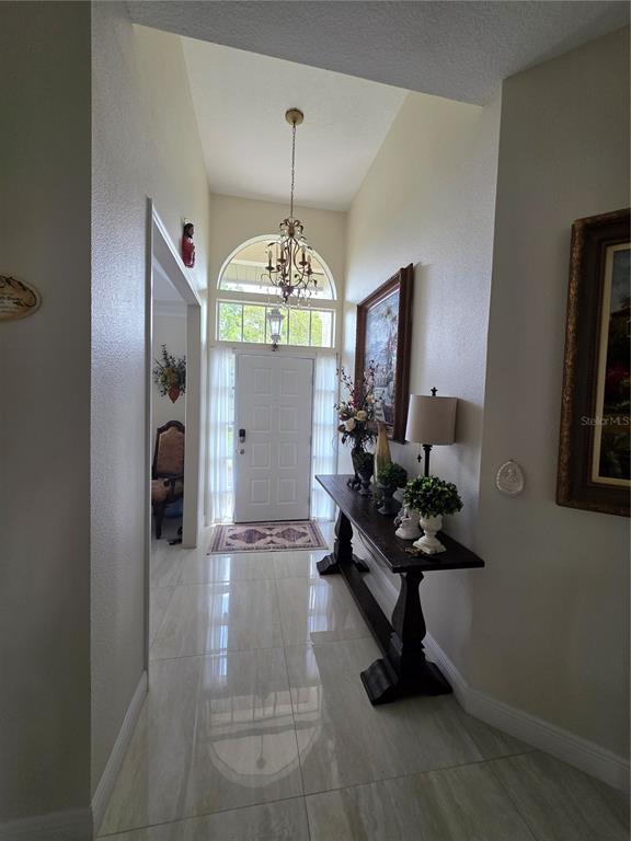 A bright entryway features a high ceiling, a chandelier, tile flooring, and a console table — 802 KAYWOOD DRIVE, ORLANDO, FL