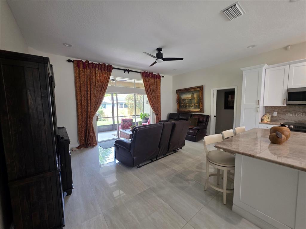 An open-concept living room features tile flooring, a kitchen island, and sliding glass patio doors — 802 KAYWOOD DRIVE, ORLANDO, FL