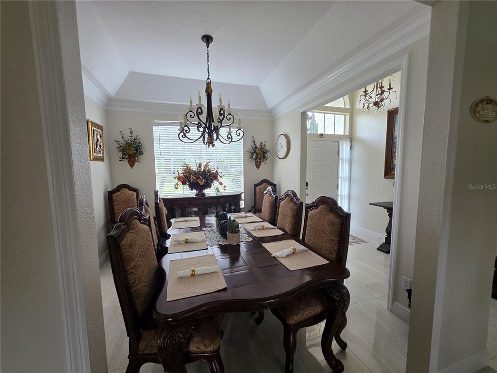 A formal dining room features a dark wood table, upholstered chairs, and a tray ceiling — 802 KAYWOOD DRIVE, ORLANDO, FL