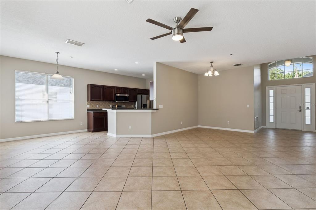 An open-concept living area with tile flooring, a kitchen with dark cabinets, and an entryway — 9957 CYPRESS VINE DRIVE, ORLANDO, FL
