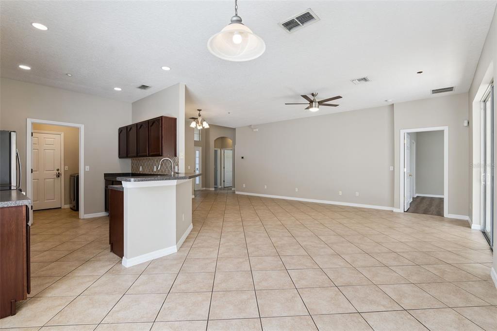 An open-concept living area features tile flooring, a kitchen island, and dark wood cabinetry — 9957 CYPRESS VINE DRIVE, ORLANDO, FL