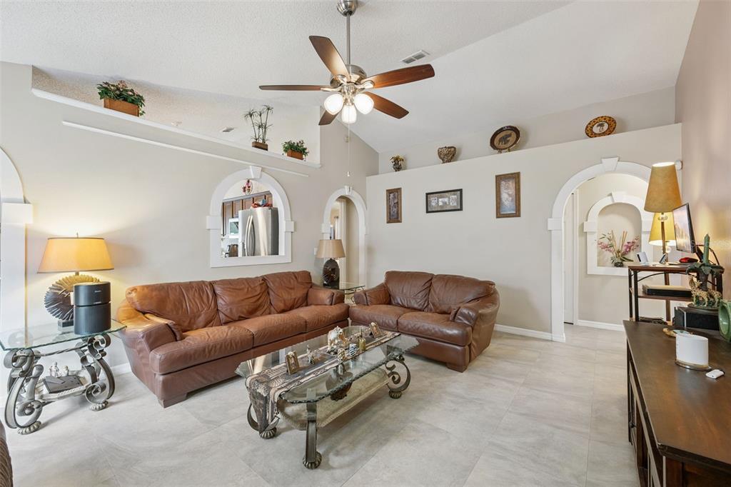 A living room features two brown leather sofas, a glass coffee table, and arched wall cutouts — 10044 RICHARDSON COURT, ORLANDO, FL