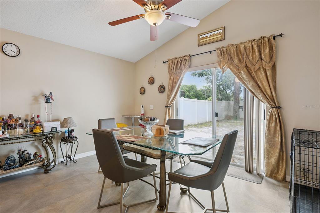 A dining room features a glass table, four chairs, a ceiling fan, and sliding glass doors — 10044 RICHARDSON COURT, ORLANDO, FL