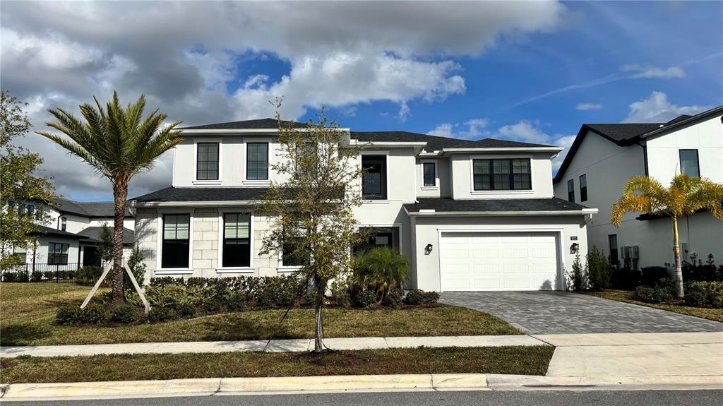 A two-story house with a white exterior, dark-framed windows, and a paved driveway — 9233 SANTORINI DRIVE, ORLANDO, FL