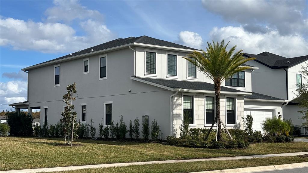 A two-story house with light gray stucco siding and a dark shingled roof — 9233 SANTORINI DRIVE, ORLANDO, FL