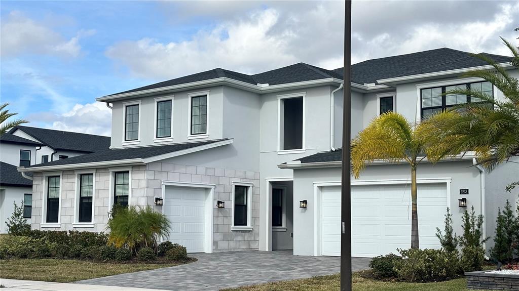 A two-story house with a gray exterior, two garages, and a paved driveway — 9233 SANTORINI DRIVE, ORLANDO, FL