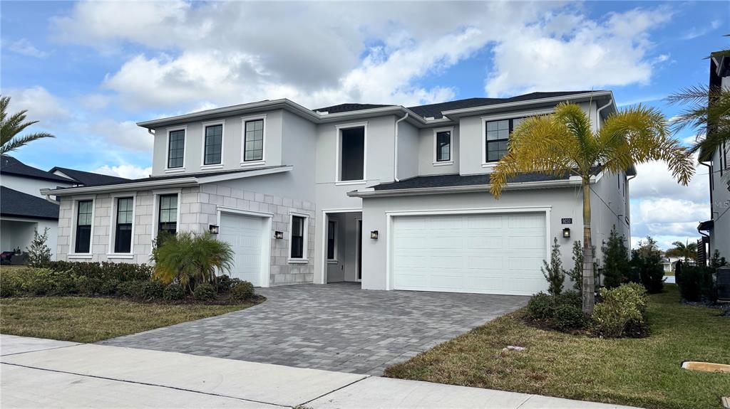 A two-story house with a gray exterior, stone accents, and a two-car garage — 9233 SANTORINI DRIVE, ORLANDO, FL