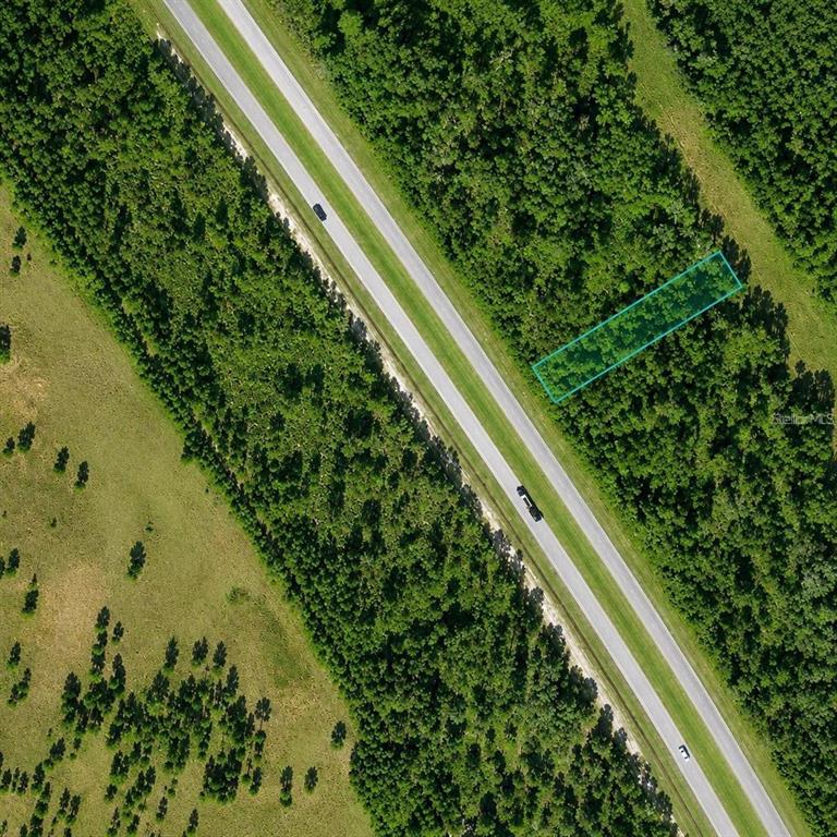 An aerial view shows a rectangular plot of land highlighted in blue beside a highway — US 27 HIGHWAY, FROSTPROOF, FL