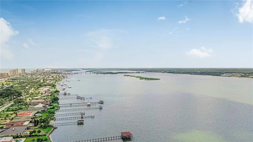 An aerial view shows a coastal residential area with multiple private docks extending into water — 3 OCEANS WEST BOULEVARD UNIT 2B2, DAYTONA BEACH SHORES, FL