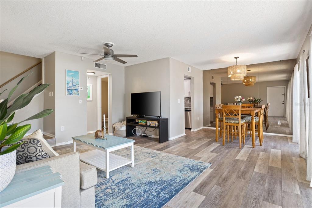 A living room with wood-look flooring, a blue area rug, and an adjacent dining area — 6305 MORNINGMIST COURT UNIT 6305, TEMPLE TERRACE, FL