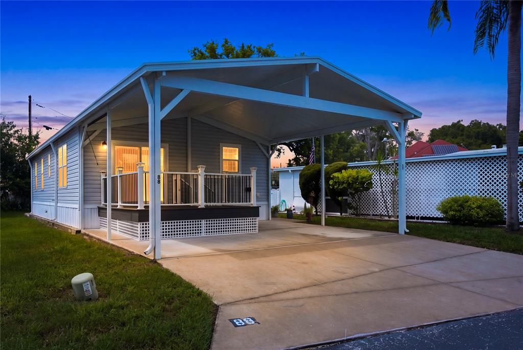 A light-colored mobile home features a covered carport, a front porch, and a concrete driveway — 980 7TH STREET NW UNIT 88, LARGO, FL