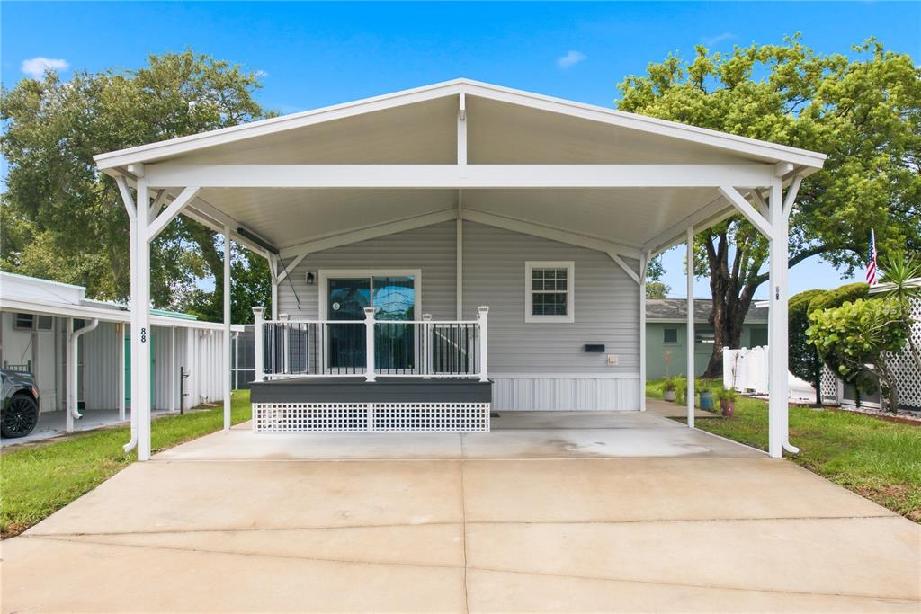 A light gray mobile home features a large covered carport and a small front deck — 980 7TH STREET NW UNIT 88, LARGO, FL