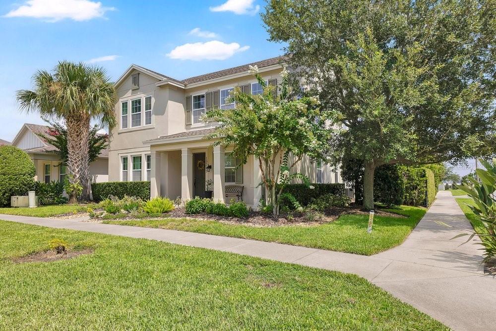 A two-story suburban house with a covered front porch, tan siding, and a landscaped yard — 15367 SHONAN GOLD DRIVE, WINTER GARDEN, FL