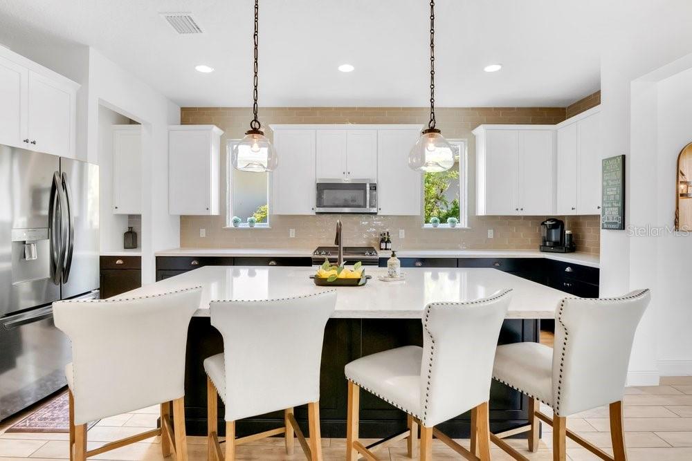 A kitchen features white upper cabinets, black lower cabinets, a large island, and light flooring — 15367 SHONAN GOLD DRIVE, WINTER GARDEN, FL