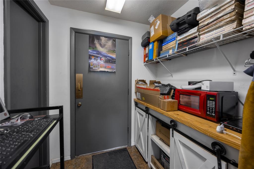 A utility room features a gray door, open wire shelving, and a red microwave on shelves — 3700 N US HIGHWAY 441, OCALA, FL