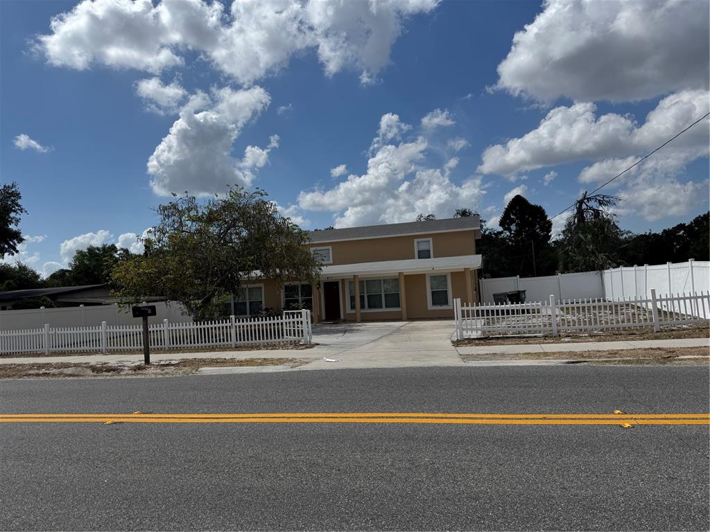 A two-story tan house with a white picket fence and a concrete driveway — 8 E SUMMIT STREET, APOPKA, FL