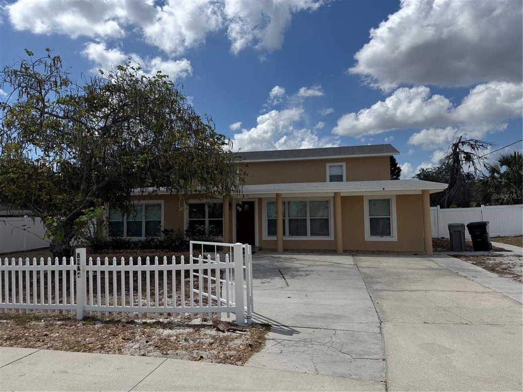 A two-story tan house with a white picket fence and a concrete driveway — 8 E SUMMIT STREET, APOPKA, FL