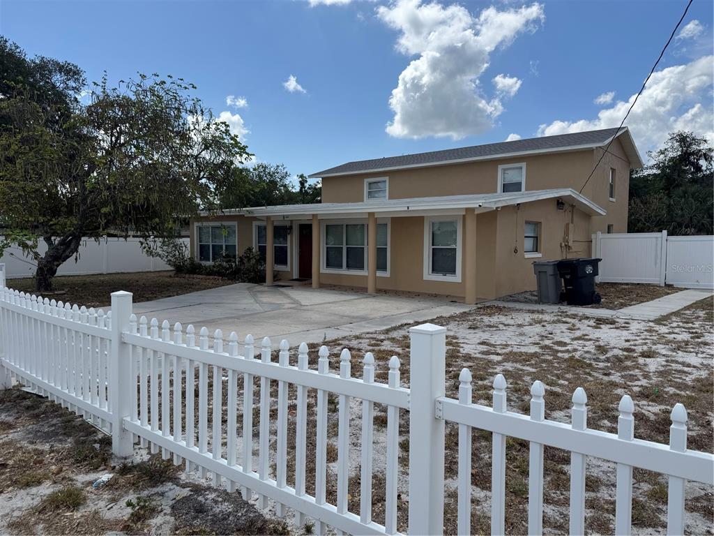 A two-story tan house with a white picket fence and a concrete driveway — 8 E SUMMIT STREET, APOPKA, FL