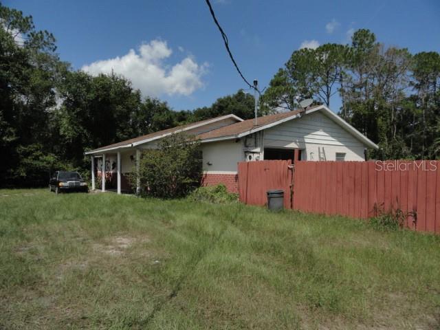 A single-story house with a red fence and a car parked on the grassy lawn — 35011 HAINES CREEK ROAD, LEESBURG, FL