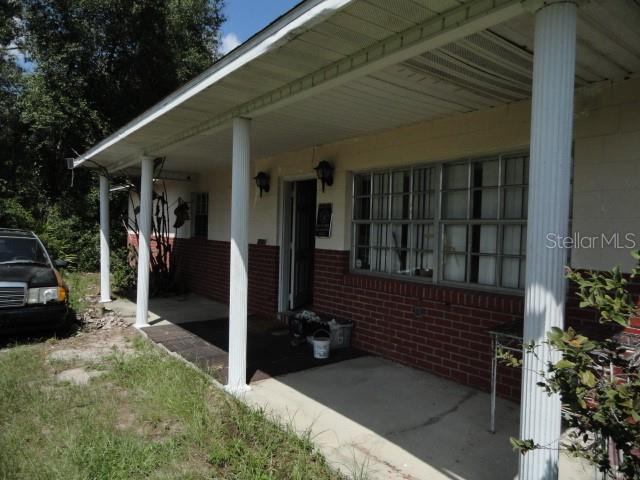 A covered front porch with white columns and a brick base leads to the entrance — 35011 HAINES CREEK ROAD, LEESBURG, FL