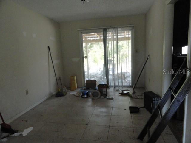 An empty room with tile flooring, a sliding glass door, and scattered cleaning supplies — 35011 HAINES CREEK ROAD, LEESBURG, FL