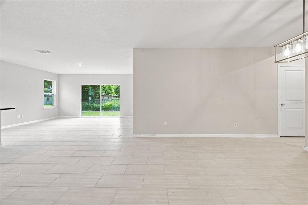 A bright, open-concept living area features light-colored tile flooring, a sliding glass door, and walls — 809 S LOCUST AVENUE, SANFORD, FL