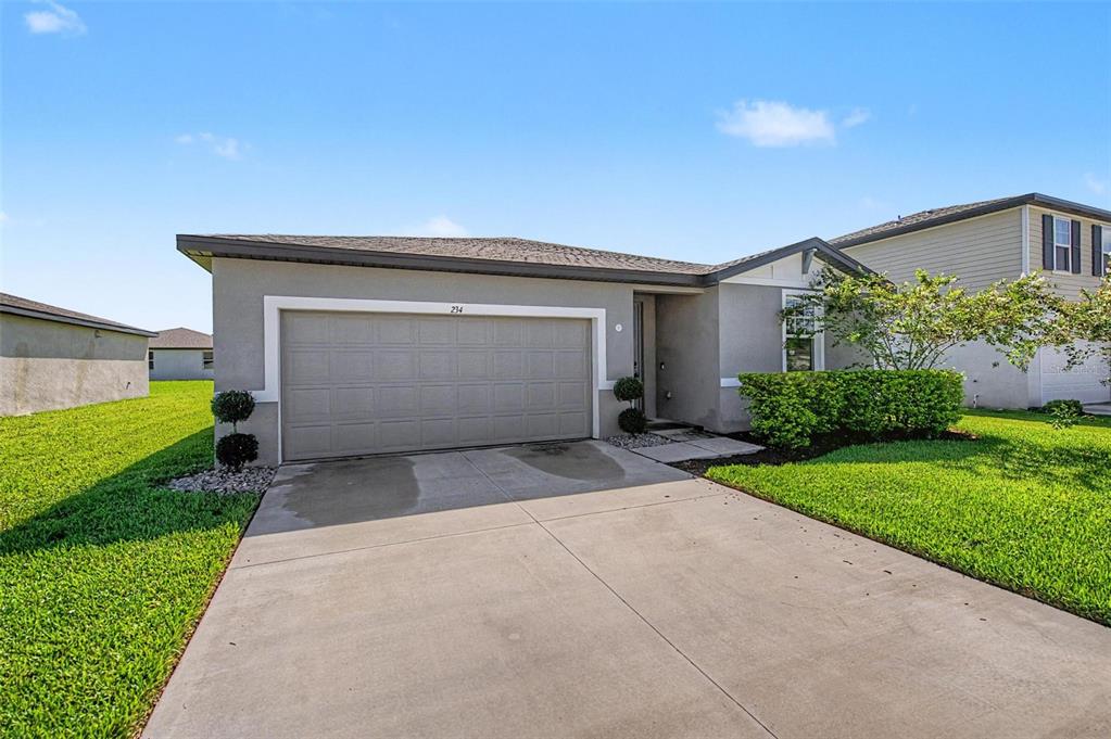 A single-story house with a gray stucco exterior, a two-car garage, and a concrete driveway — 234 LOVELY COURT, PLANT CITY, FL