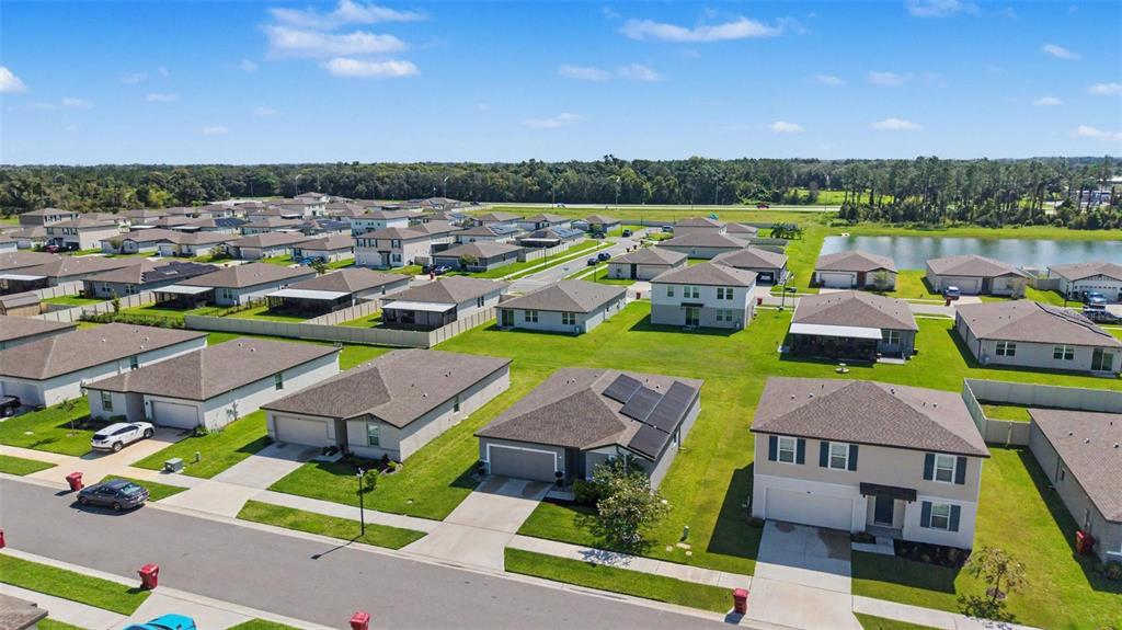 An aerial view shows a suburban neighborhood with single-family homes, green lawns, and a pond — 234 LOVELY COURT, PLANT CITY, FL