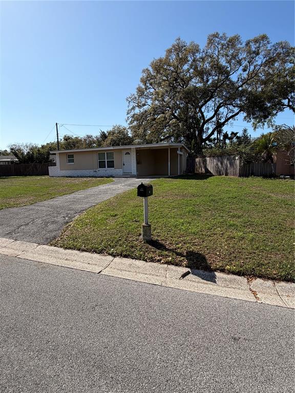 A single-story house with a driveway and a mailbox stands on a grassy lot — 972 CEDARWOOD AVENUE, DUNEDIN, FL