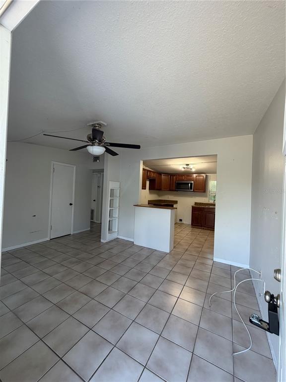 An open-concept living area with tile flooring leads into a kitchen with wood cabinets — 972 CEDARWOOD AVENUE, DUNEDIN, FL