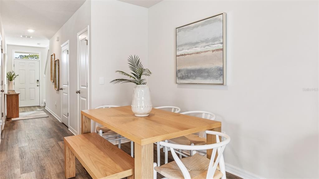 A dining area features a wooden table, a bench, and white chairs near a hallway — 7776 42ND LANE N, PINELLAS PARK, FL