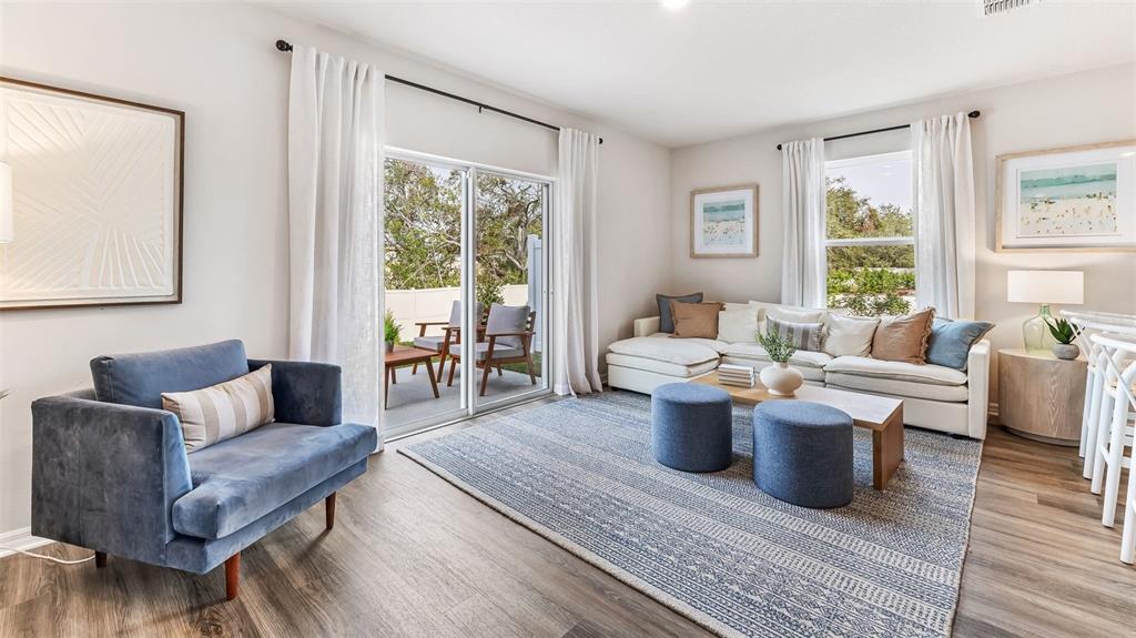 A living room features a blue armchair, a sectional sofa, and a sliding glass door — 7776 42ND LANE N, PINELLAS PARK, FL