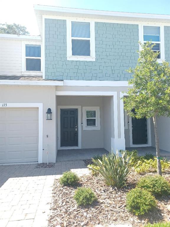 The exterior of a two-story townhouse features light blue shingle siding and a paved driveway — 173 RIVER FRONT WAY, EDGEWATER, FL