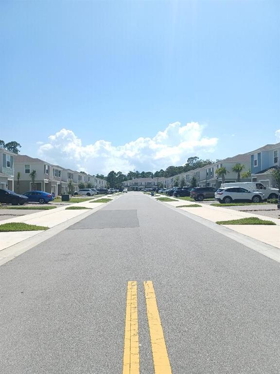 A street view of a residential neighborhood with townhomes and parked cars on both sides — 173 RIVER FRONT WAY, EDGEWATER, FL