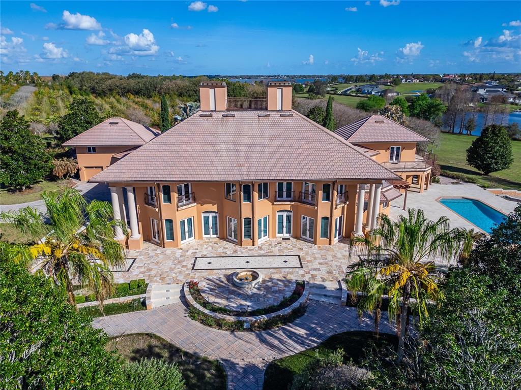 An aerial view of a large, multi-story peach-colored house with a pool and patio — 501 ADAMS BARN ROAD, AUBURNDALE, FL