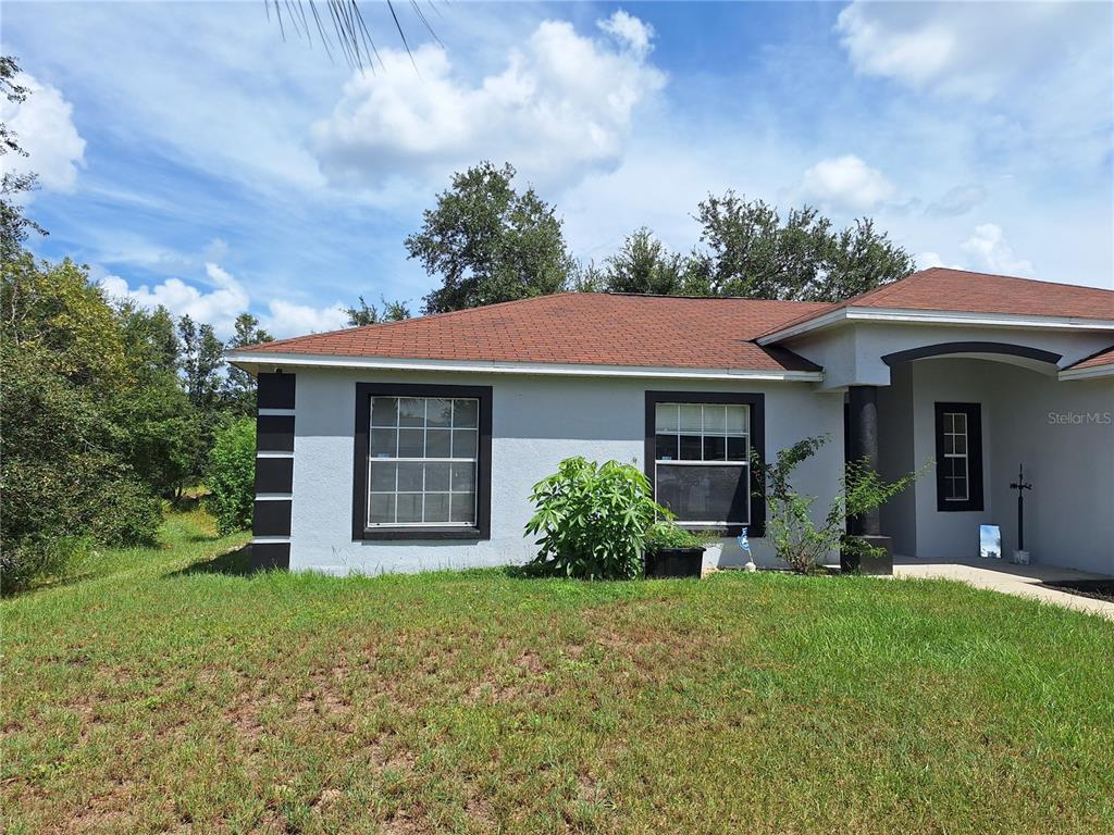 A single-story house with a light-colored stucco exterior, dark trim, and a brown shingled roof — 327 PUFFER COURT, POINCIANA, FL