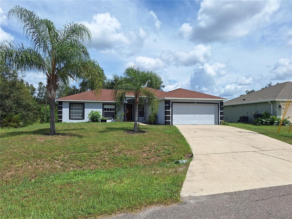 A single-story house with a white garage, gray exterior, and two palm trees in the yard — 327 PUFFER COURT, POINCIANA, FL