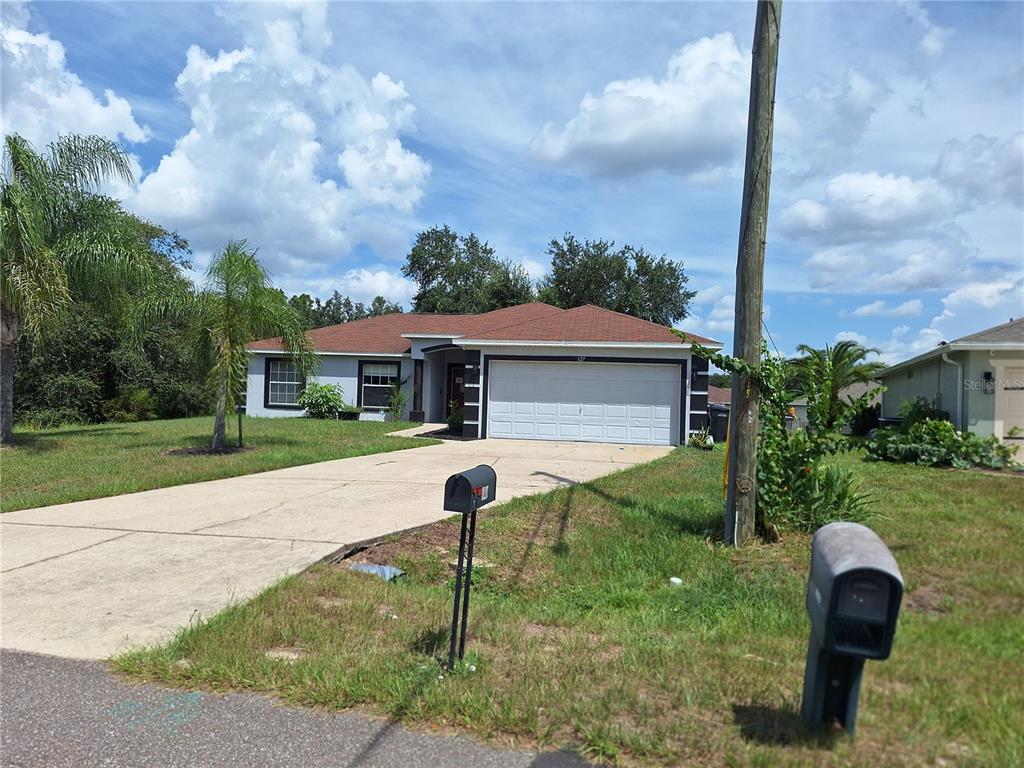 A single-story house with a two-car garage, a concrete driveway, and two mailboxes in front — 327 PUFFER COURT, POINCIANA, FL