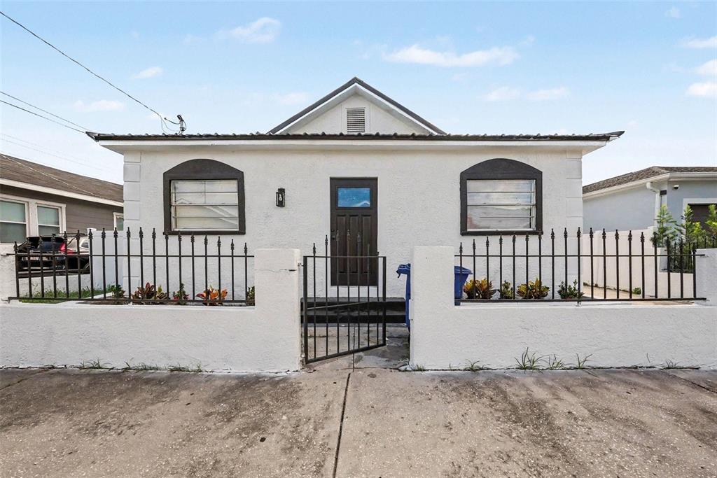 A white single-story house with a dark door and metal fence behind a concrete driveway — 2923 SANCHEZ STREET, TAMPA, FL
